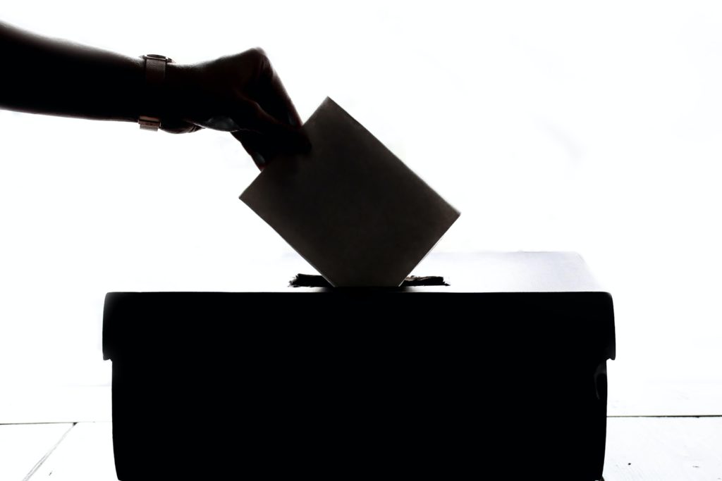 Hand inserting ballot in ballot box